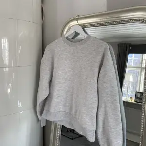 En ljusgrå sweatshirt i storlek xs från Gina tricot.