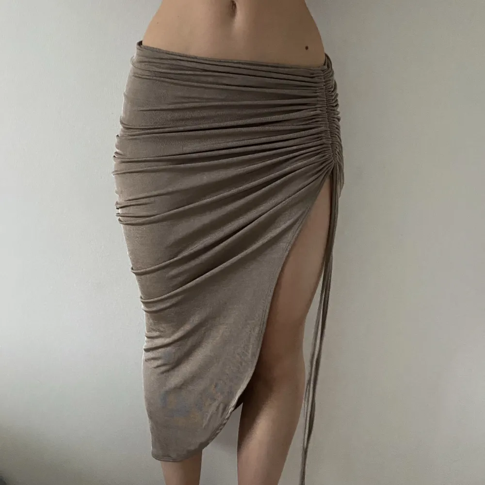 Kjol med slits i glittrigt beige tyg. Ej genomskinlig. Stretchiga Passar xs/s/m. Bra skick. Nypris: 450 kr Säljer för: 200 kr. Kjolar.