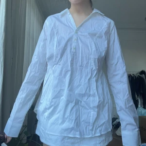 Vit skjorta - Size L. helt ny oanvänd, endast provad för bilden. möts i stockholm eller fraktar. det är en vit kjol under på bilden.