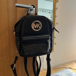 Mk väska, svart 🕺 - Superfin väska som jag till 99% är säker inte är äkta. Men den är superfin och kul ändå. Bara legat i garderoben i en evighet, därav säljs den. Superbra skick. Man kan ta bort banden och göra den till en axelremsväska! Frakt tillkommer!