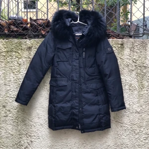 Hollies Livingo Svart/Svart - Hollies Livigno är en  dunjacka tillverkad i polyester, foder i polyester och med en varm fyllning med 80 % dun och 20 % fjäder.  Äkta päls  Använd jackan 8 gånger. Köptes förra vinter  Ny pris 4500kr  Det är en lite liten repa vid ena ärmen   