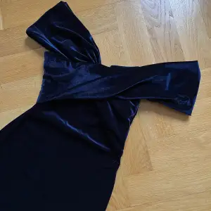Väldigt snygg åtsittande klänning i lyxigt sammets material. Vackert dekolletaget och ärmkanter man själv kan placera hur man vill. Fin mörkblå färg och man känner sig het i den.