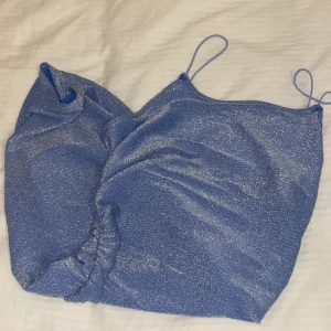 Klänning - En glittrig blå klänning.  Vet inte vart den är ifrån men det är storlek xs. Jätte fin med smala band vid axlarna. Aldrig använt den. Säljer för 100kr 