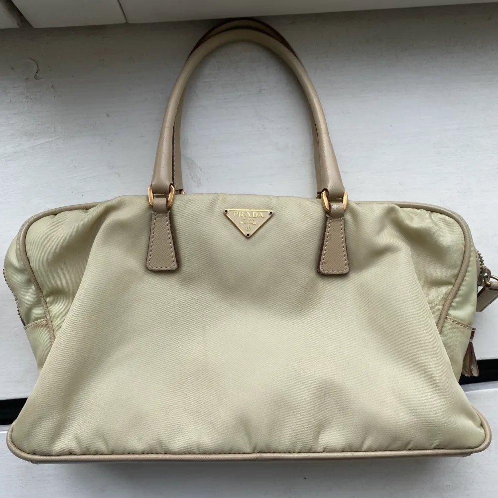 Säljer med sorg världens finaste crème/beige vintage Pradaväska. Otroligt fint skick. En liten söm har gått upp i innertyget men det går att fixa superenkelt hemma alternativt kan jag ta den till en skräddare innan försäljning för 200:- extra. 🤍. Laukut & Käsilaukut.