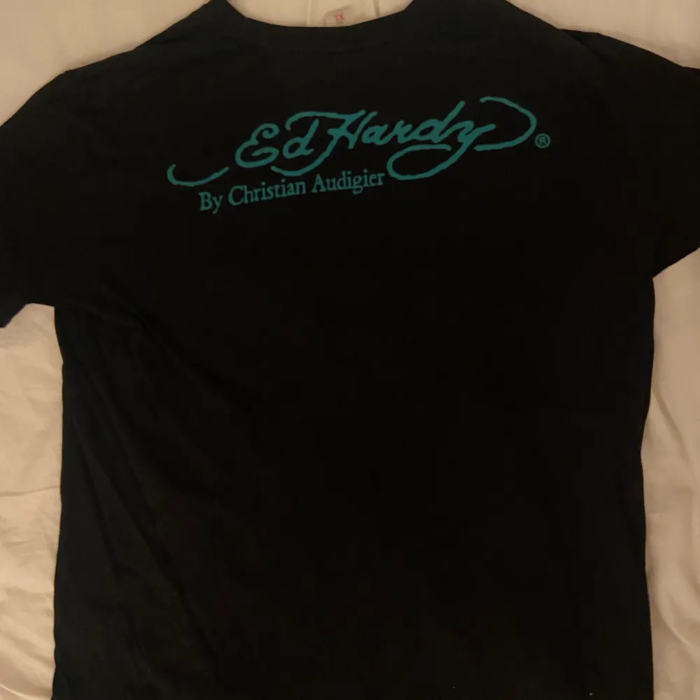 Säljer en vintage Ed Hardy T-shirt i svart färg med ett multifärgat tryck. Baksidan har även märket på :). Storleken är XL men passar mindre storlekar som perfekt oversized.. T-shirts.