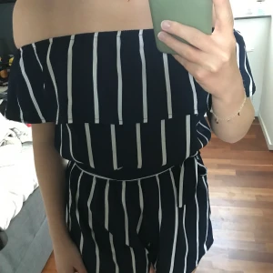 Jumpsuit / byxdress  - En randig jumpsuit/byxdress i storlek XS/S. Den är mörkblå med vita ränder, se bild 3. Har ett avtagbart band som man kan sätt runt t.ex. midjan eller i håret. Bild 1: med band. Bild 2: utan band. Har ett resår i midjan. Helt oanvänd. 