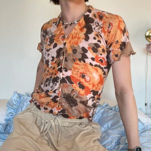Orange brun beige stickad kofta blommig - Vintage orange, aprikos, brun och beige kortärmad stickad kofta med lettuce hem och det finaste blommiga mönstret 🧡🤎 Älskar hur den sitter och att den är så skön! Man kan ha den som den är eller öppen med ett spetsning under samt ett par bruna manchesterbyxor eller vanliga utsvängda jeans för en avslappnad outfit! :D