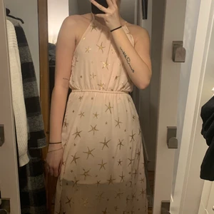 Rosa långklänning med guld stjärnor - Denna långklänning har jag använt en gång så den ä i väldigt gott skick. Den har en urringning som går upp rätt högt i halsen samt att den har ett insytt band vid magen som är väldigt stretchigt.🤍 Klänningen är ganska lång och har slits på båda sidorna, och som man kan se på bilden så är det även en under klänning som slutar ungefär vid knäna och sen ett tunnare tyg ovanpå🤍