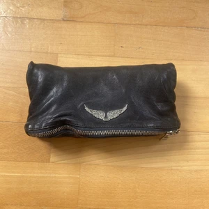 Väska från Zadig & Voltaire  - Säljer min väska från Zadig & Voltaire som inhandlades för några år sedan från deras butik på Birger Jarlsgatan (därav äkta). Inga direkta märken av användning, förutom att den långa kedjan är sönder, skickar med den ändå då den kan användas till skärp eller dylikt. Den korta kedjan går att använda och är ca 60 cm, utsträckt på golvet. Väskan går även att användas som ”Clutch”, dvs utan kedjor. Väskan är i läder och i bohemisk stil. Måtten är ca 12x23 cm. 