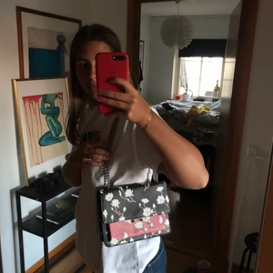 Mönstrad väska  - Väska i mörkblå och rosa med vit blommor på. Den är i mycket bra skick!