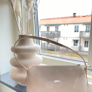 Väska från H&M  - Axelväska från H&M. Den är beige med lite inslag av ljus rosa & lack material. Aldrig använd. 