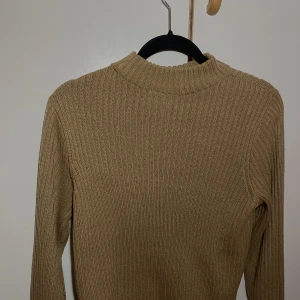 Polotröja  - Knappt använd. Beige/brun halv polo. Lite kort vid magen. 