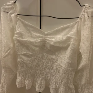 Vit spets topp - Vit spets topp från NA-KD! Den är offshoulder samt lite kortare. Säljer pgr av att den aldrig kommer till användning. Strl S, skriv för mer information💗