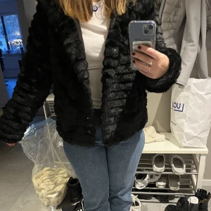 Jacka fuskpäls  - Säljer min ”päls”jacka. Jättemysig jacka med stor luva. Säljer eftersom den inte kommer till användning. Sparsamt använd utan defekter. Köpt på bubbelroom 899kr nypris. Storlek 38, passar både M och S. Knappar och fickor. 