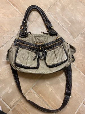 Väska  - Snygg väska. Två innerfack och massa småfack. Den har några få defekter. Om man vill köpa via swish står köparen för den eventuella extra fraktkostnaden