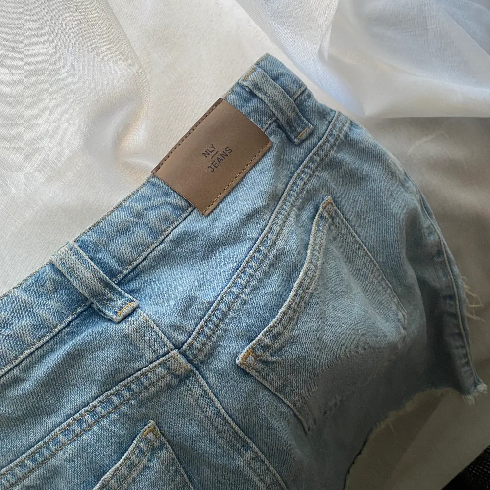 En jeanskjol i ljus jeans färg från Nly. Stora snygga slitningar i fram. Storlek 34. Kjolar.