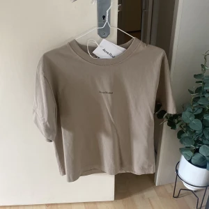 T-shirt - Acne t-shirt i en skitfin beige färg med loggan över bröstet. Använd 1 gång därav säljer ja den. Köpare står för frakt. För mer info & bilder kontakta mig 🫶🏿