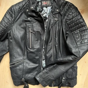 JOFAMA skinnjacka - Skinnjacka i äkta skin med ”nitar” på axlarna och bälte. Från jofama by kristine ullebø. Väldigt fint skick i strl 38