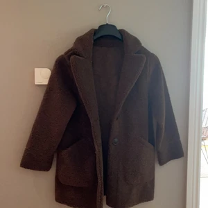 Brun kappa  - Barnkappa i teddy material. Går att vända ut och in då blir det Mocca. Knappt använd, som ny. 