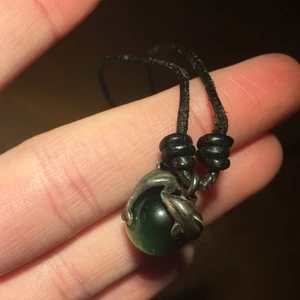 Halsband med glaskula - Säljer detta läderhalsband med två delfiner runt en grön glaskula då det inte kommer till användning! 🥰