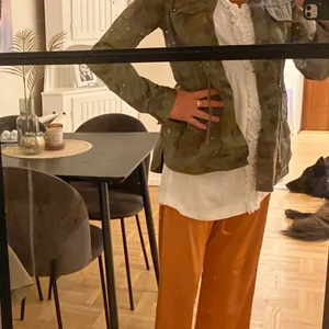 Kamouflage jacka - Kamouflagejacka med lite urblekt effekt på tyget i mycket fint skick. Går att dra åt band i midjan. 