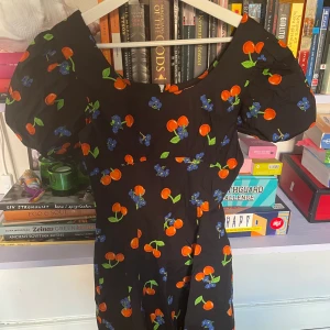 Klänning med körsbär  - Klänning med puffarm och dragkedja i ryggen. Aldrig använd 