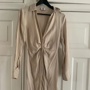 Beige klänning från NA-KD  - Superfin figursydd klänning från NA-KD. Sitter superfint över midjan eftersom modellen är sydd för att framhäva midjan/höfterna. Går ovanför knäna. Storlek 34