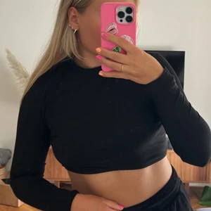 Svart långärmad croppad tröja  - En svart långärmad croppad tröja från Nelly som är lite högre i halsen och går upp lite längst ned framtill! Storlek M. Använd en gång, superfint skick ⭐️🖤