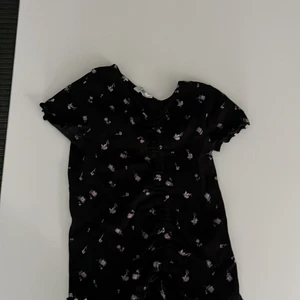 En blomrig t-shirt - En svart blomrig t-shirt i storlek 170 och den är ganska kort vid armarna och är ihopsydd därfram 