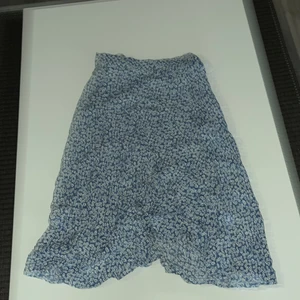 En marinblå kjol med vita blommor - En marinblå kjol med vita blommor på den är i storlek S