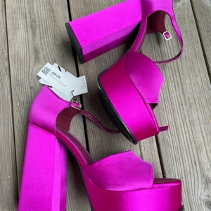Zara trendig platåklack strl 40 - Aldrig använda platåklackar från Zara strl 40. I nyskick, fantastisk fin färg och true to size. 13 cm klackhöjd.  Från Zaras hemsida:  Högklackade platåsandaler. Glansigt tyg. Knäppning med vristband. Spänne på vristen.