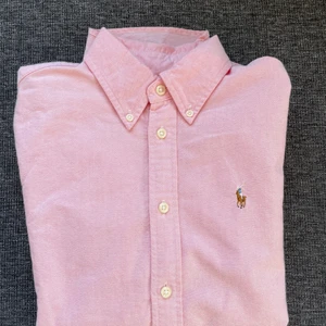 Ralph Lauren skjorta stl XS  - Rosa RL skjorta i fint skick. Använd ett fåtal gånger. Säljer den pga för liten. Tycker den är såå snygg till ett par jeans!  Den är 100% bomull och extra knappar medföljer.  Frakt tillkommer. 