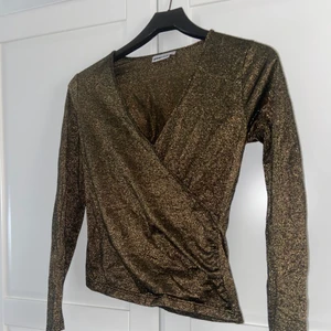 Guldglittrig topp ifrån ginatricot - Hej! Säljer denna fina topp ifrån ginatricot. Säljer pga ingen användning, aldrig använt denna topp 🤍