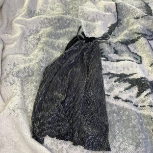 En fin liten festligare topp  - Här har vi en liten festligt topp som är svart och har lite glitter typ har använt det typ 1-2 gånger och är även öppen i ryggen 