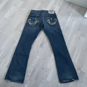 Bootcut True Religion - Ett par vintage bootcut true religion jeans med camo detaljer på bakfickorna. Storlek 30.