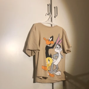 Tröja  - Jag säljer en beige/brun tröja från hm!  Med 1 anka 1 kyckling och 1 hare/kanin. I storlek 134-140. Tröjan har tyvärr en liten fläck som är svart. Men som knappt syns 👕💯