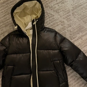 Svart Puffjacka  - Säljer en egendesignad jacka från H&M! Nypris var 799. Svart ytterfoder och ljusgult/ inuti🫶 den är endast testad så helt nyskick! Säljer pga har en annan liknande 💖 den är i storlek XS. Jag pendlar mellan XS och S och den passar mig bra. Är 167cm lång💘 