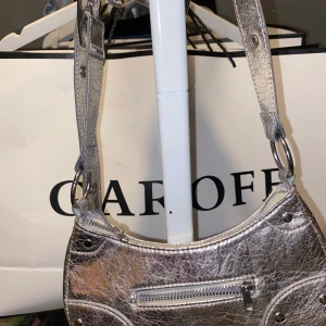Silver  - Helt ny Silver väska från h&m man kan justera bandet