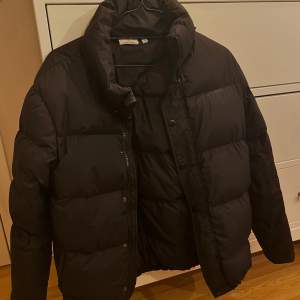 Svart Puffer jacket i storlek 40. Köpt vintern 2021 och är använd varsamt. Jackan är i gott skick, nypris är 2 199 kr.