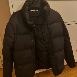 Vinter jacka - Svart Puffer jacket i storlek 40. Köpt vintern 2021 och är använd varsamt. Jackan är i gott skick, nypris är 2 199 kr.
