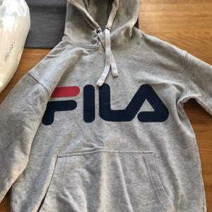 En grå Fila hoodie i strlk XS, lite trasig på höger ärmen eller vad det heter (se bild)
