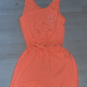 Aprikos/neon orange jumpsuit/byxdress - Aprikos/neon orange jumpsuit/byxdress från H&M! Använd 1 gång, på en sommaravslutning för ungefär 2 år sen! Som nytt skick! Jättefin färg nu på sommaren. 🥰🧡💗
