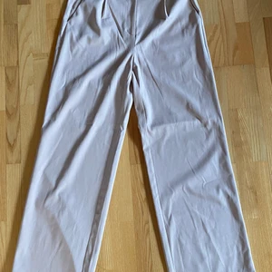 Raka beige kostymbyxor - Raka beige/puderrosa kostymbyxor. Passar någon som är 165-175cm. Lite slitningar i tyget i bak på ena benet, se bild. Annars fint skick! Köpare står för frakt. Hör av dig vid intresse.
