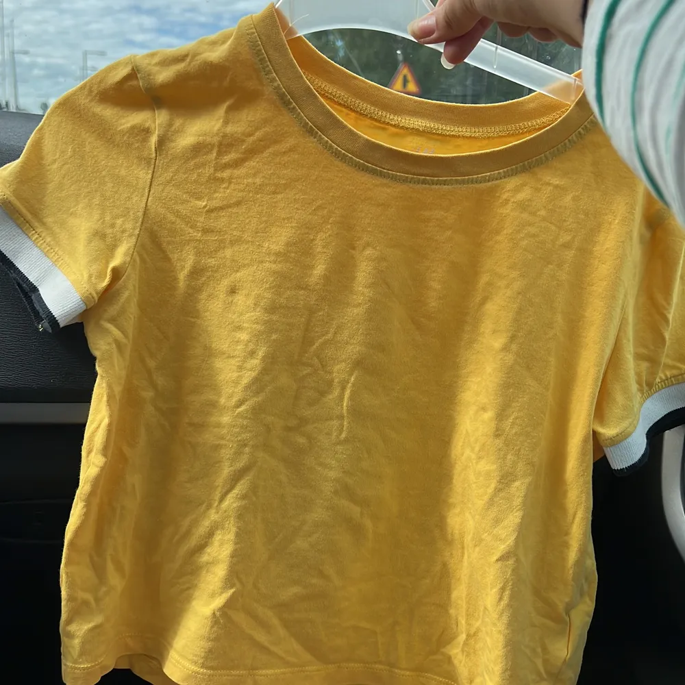En gul t-shirts magtröja med ränder på ärmarna . T-shirts.