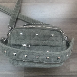 Noella väska  - Säljer min Noella väska, den är grön med silvriga nitar. Man får plats med lite smink och telefon mm💗💗den är i nyskick då jag bara använt den få gånger. Säljs inte längre och köpt för 800kr❤️
