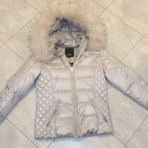 Ny Rock & Blue Vinterjacka Äkta päls stl 36-40 - Super snygg limited edition jacka från Rock & Blue stlk 40 men mer som en 36/38. Pärlemor färg med äkta avtagbar päls i luvan. Gulddetaljer. Pris 2500:-, kan diskuteras vid snabb affär