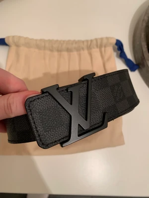 Louis Vuitton Initiales Damier Graphite - Säljer mitt LV bälte p.g.a brist på användning, bältet är i väldigt bra skick. Det är köpt i Moskva på LV butik och kvitto medföljer. Köpte det för 4500kr. Storlek 85/34 Mer bilder kan skickas.