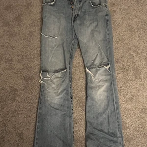 lågmidjade jeans lee - säljer nu dessa unika jeans från märket lee, de sitter lågmidjat med hål på knäna och lite slitningar. byxorna är väldigt slitna som man ser på bild nr 3 för de är väldigt långa. Det syns dock inte så mkt eftersom det är på baksidan.
