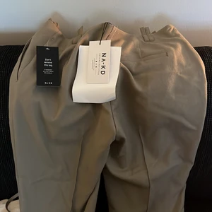 NA-KD byxor oannvända - Säljer mina beige/bruna byxor från NA-KD i storlek 36, helt nya alla lappar kvar! Toppskick!