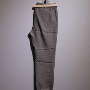 Cool light trousers in a light olive green with stretch band above the ankles. Never been worn. 